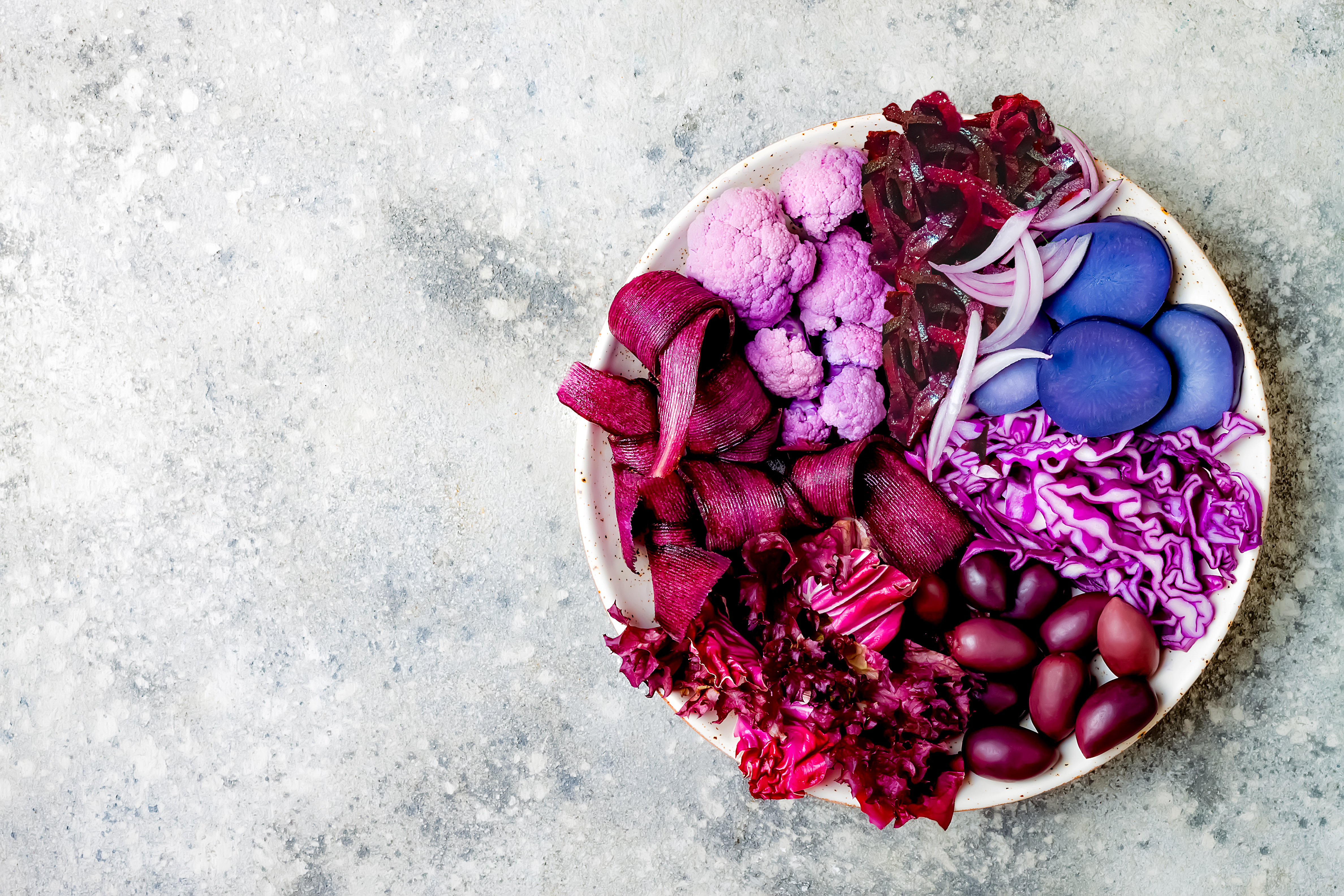 Platter of vibrant purple and pink fermented vegetables — cauliflower, beetroot, red cabbage, radicchio, and kalamata olives